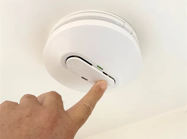Hand interacting with a photoelectric smoke alarm